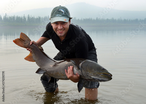 Happy man - success angler holds a big fish photo