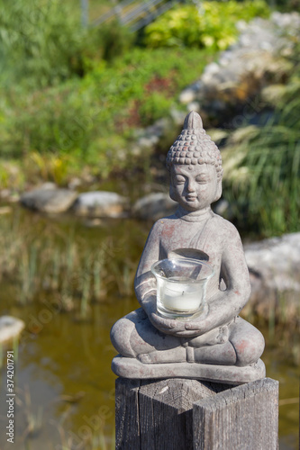Buddha statue on the natural background. Sunny morning in the park. Summer background for meditation and relaxation