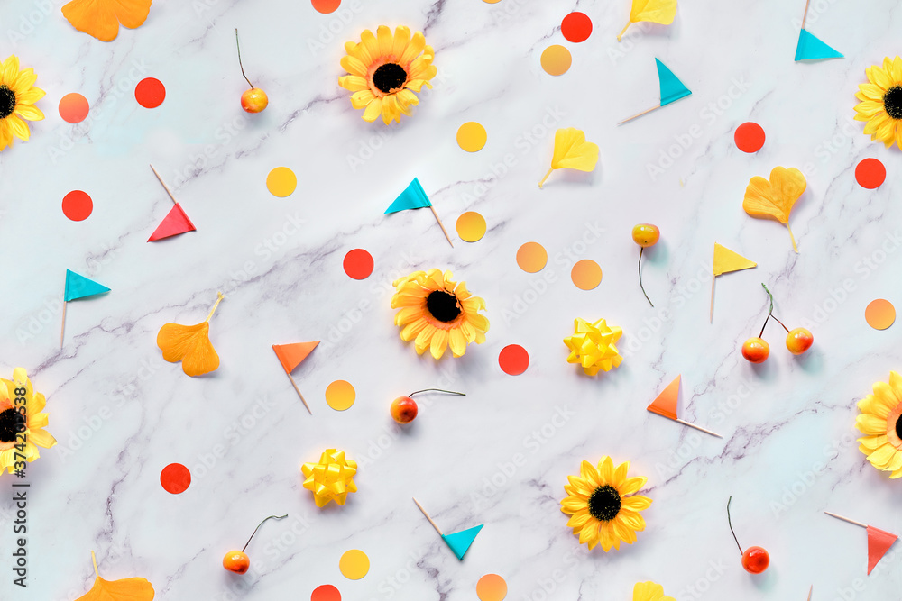 Abstract Fall seasonal background with yellow flowers, Autumn gingko leaves, paper confetti and toothpick flags. Flat lay on white marble table.