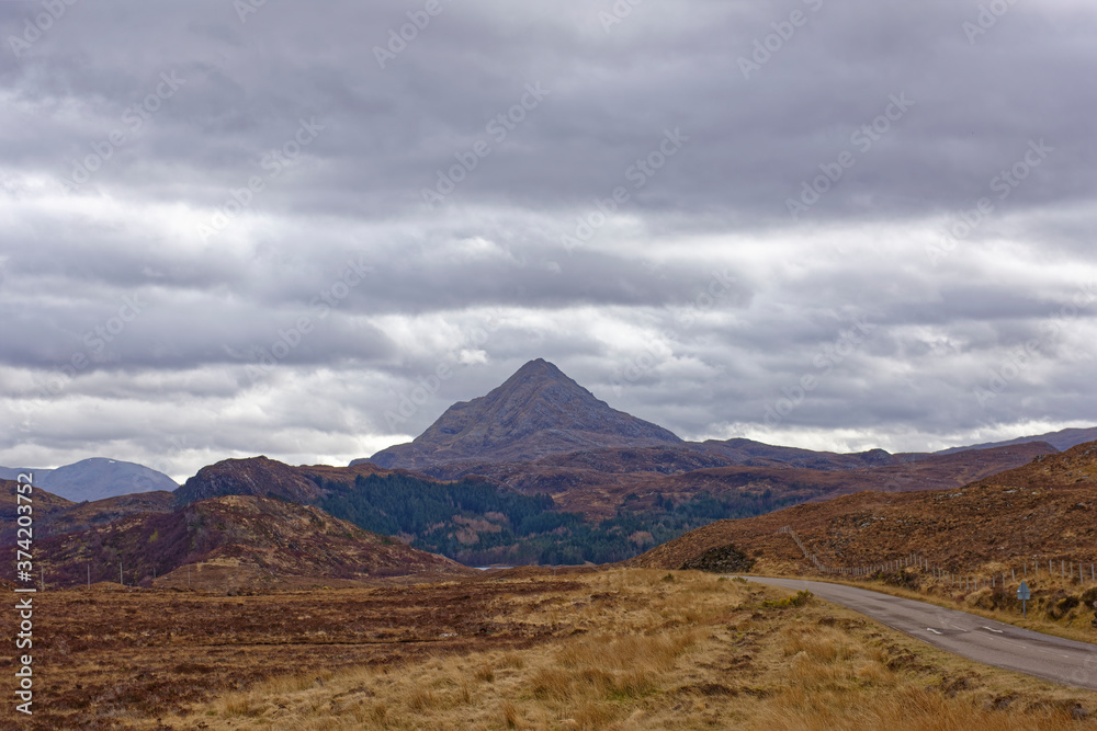 Dramatic Mountain Scenery on the road through the North West Highland Global Geopark in Assynt, with a triangular peak in the background.