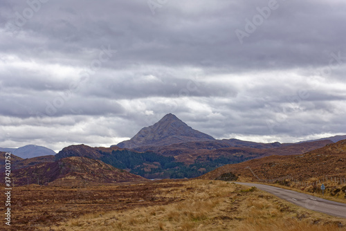 Dramatic Mountain Scenery on the road through the North West Highland Global Geopark in Assynt, with a triangular peak in the background. © Julian