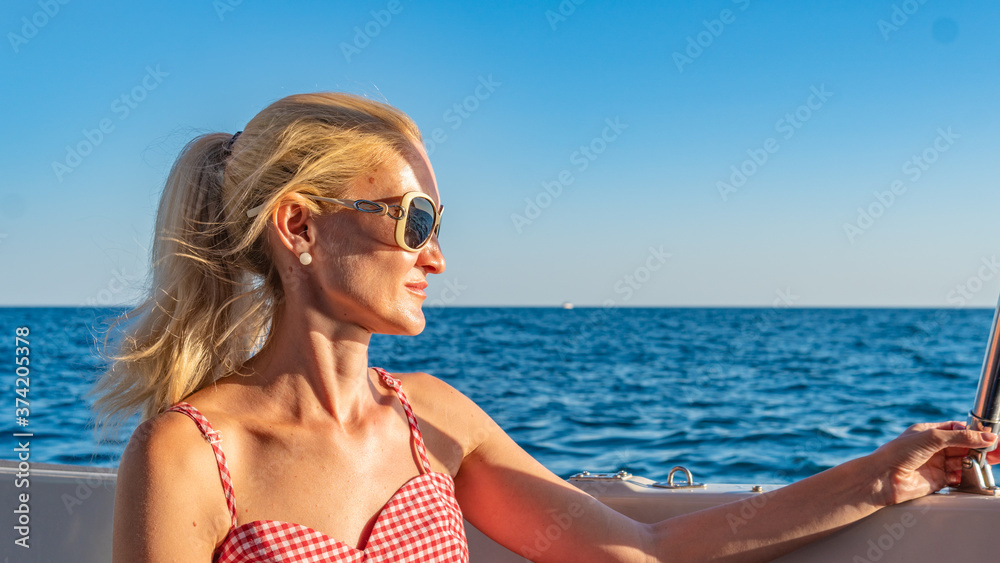 Cheerful girl resting on a yacht, with tender lips around the sea, the concept of comparison in sunglasses beautiful horizon