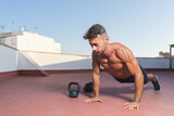 Athletic and muscular man doing push-ups during a fitness session  on the terrace of his home