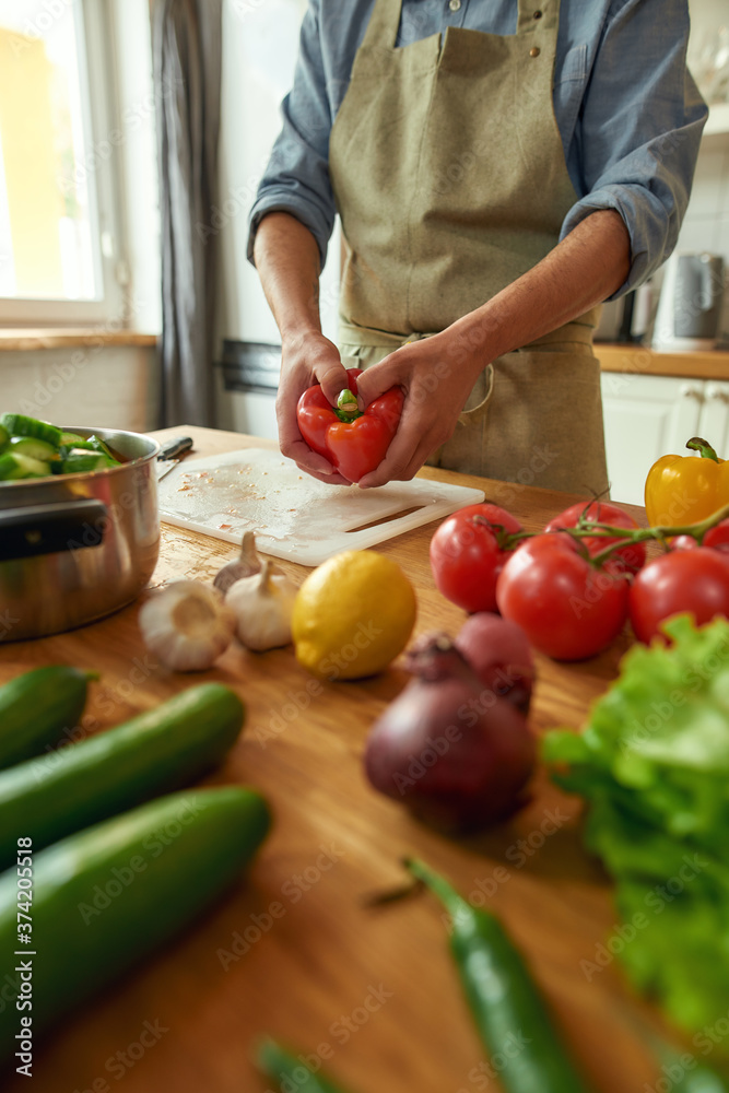 Close up of hands of man preparing pepper to use in cooking healthy meal, soup in the kitchen. Italian cuisine concept Close up of hands of man preparing pepper to use in cooking healthy meal, soup in the kitchen. Italian cuisine concept