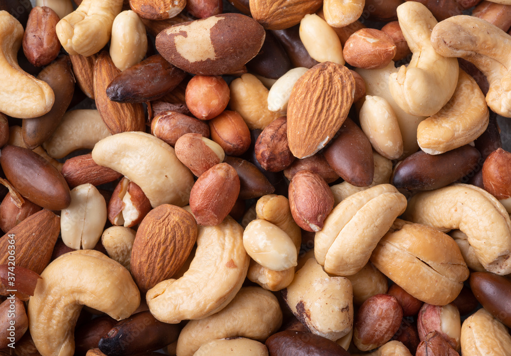 Closeup top view of mixed nuts over a wooden background. Peanuts, brazilian nuts, cashew nuts, baru nuts and almonds