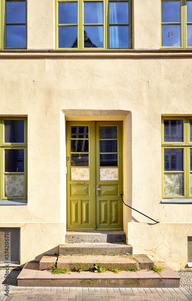 Light green wooden door and window as an entrance in an old house. Light green wooden door and window as an entrance in an old house.