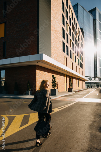 Young stylish woman, walking on office buildings background. Business concept.