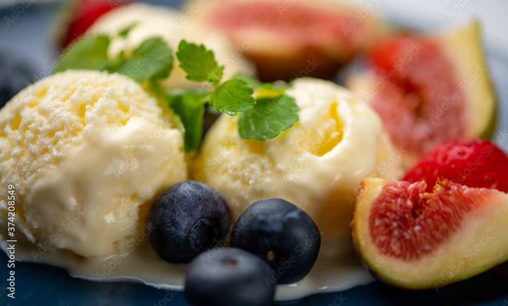 three scoops of ice cream, figs, blueberries, and a mint leaf on a blue plate three scoops of ice cream, figs, blueberries, and a mint leaf on a blue plate