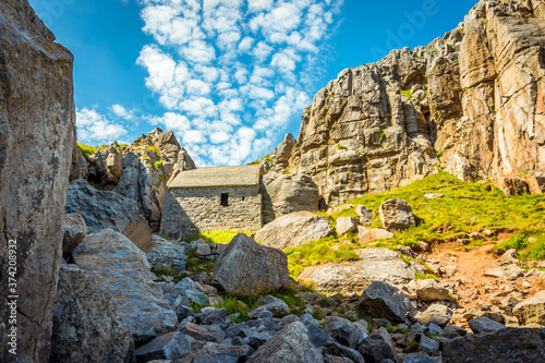 The ruins of St Govans Chapel with cirrus cloud formation in the background on the Pembrokeshire coast in early summer photo