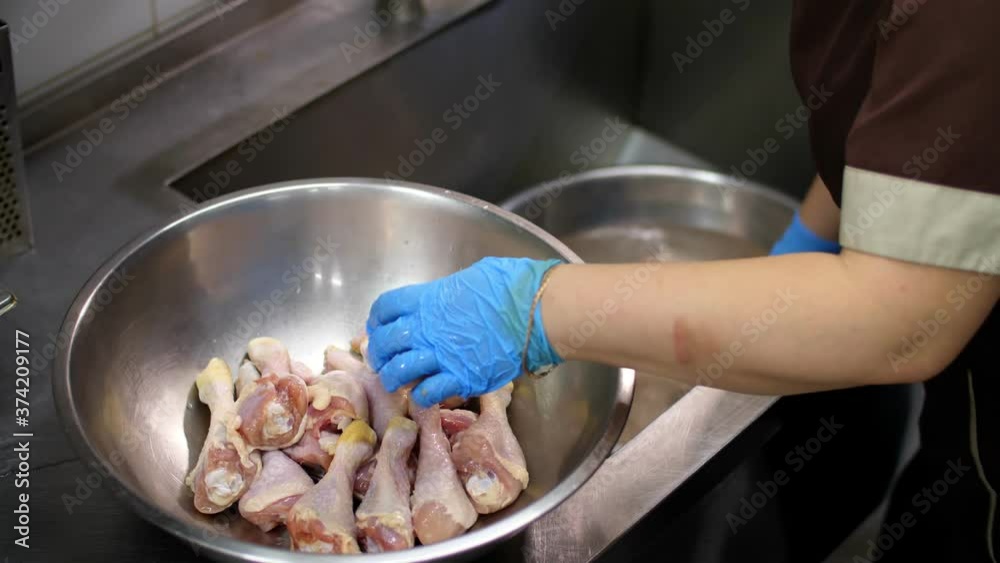 close-up. cuisine worker, in protective gloves, washes raw chicken legs before cooking. health food. volunteering and charity. reopening after covid-19. safety concept. close-up. cuisine worker, in protective gloves, washes raw chicken legs before cooking. health food. volunteering and charity. reopening after covid-19. safety concept.