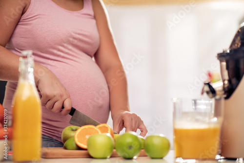 Pregnant woman make fresh orange juice