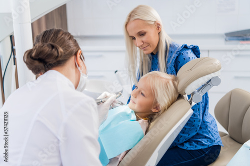 A mother watching a dentist taking care of her little daughter's teeth.