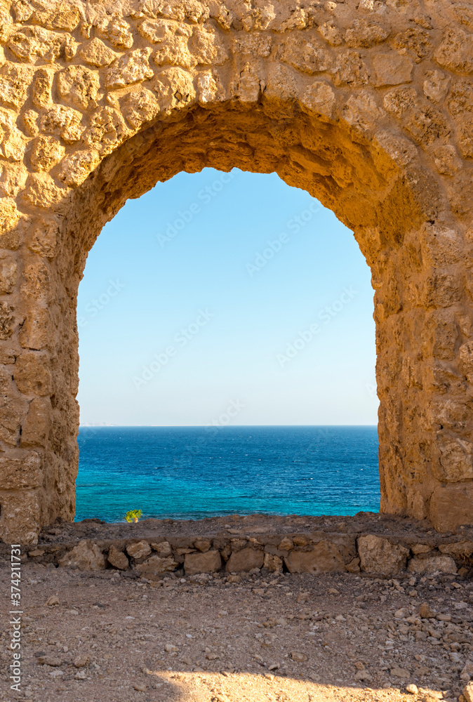 beautiful summer view of the blue sea and palm trees through the arch
