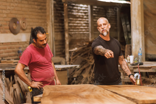 Amigos carpinteros trabajando en equipo con madera en taller de carpintería