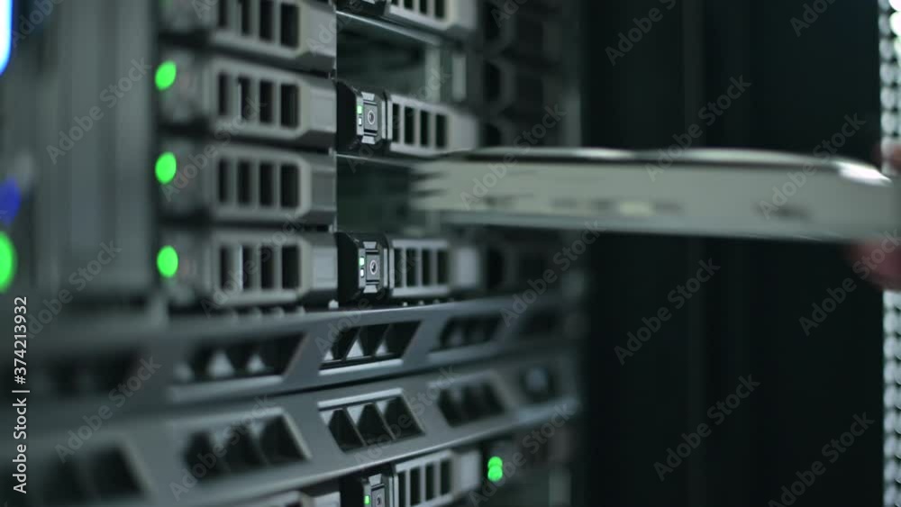 the sysadmin and server master pulls the hard drive out of the system by pressing a button and removing it. Close-up. information recording process
