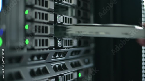 the sysadmin and server master pulls the hard drive out of the system by pressing a button and removing it. Close-up. information recording process