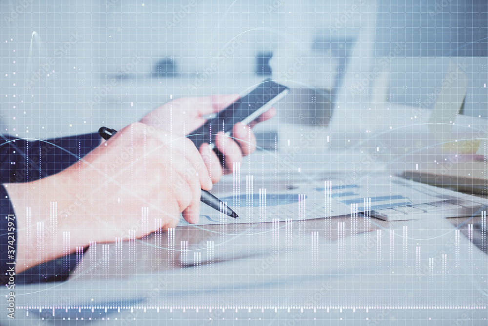 Double exposure of man's hands holding and using a phone and financial graph drawing. Analysis concept. Double exposure of man's hands holding and using a phone and financial graph drawing. Analysis concept.