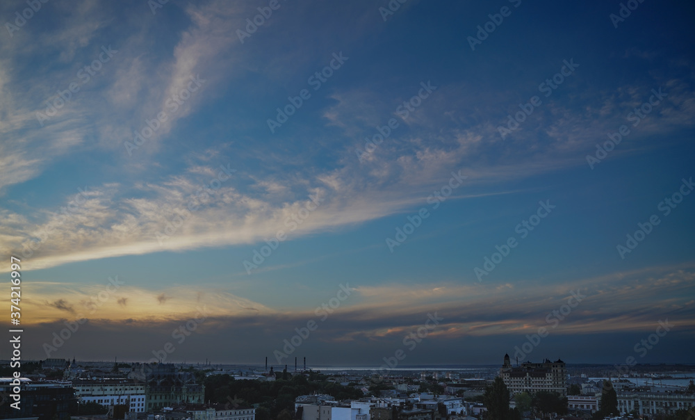 Sunset with stripes of white and orange clouds over the city with the bay