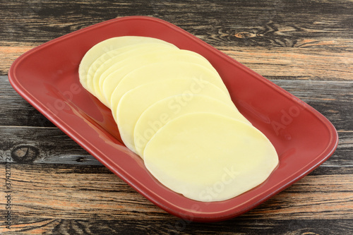 Provolone cold cut cheese slices on red serving platter on table