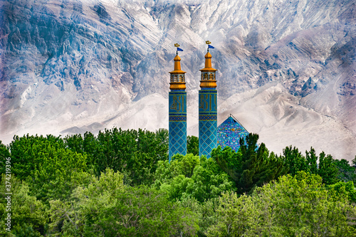 Iran, in the oasis of Rayan ( district of Kerman), In the middle of the desert the beautiful blue coloured mosque Shir-e Khoda. Surrounded by green vegetation. A dry rock mountain in the background. 