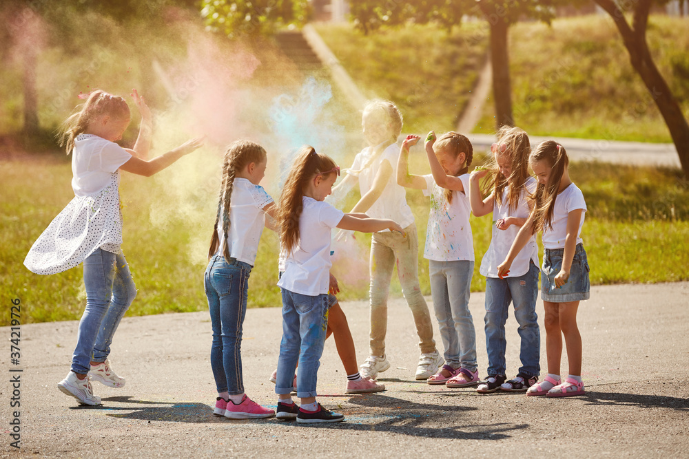 Naklejka premium Happy smiling girls have fun using Holi colors, in the summer at sunset