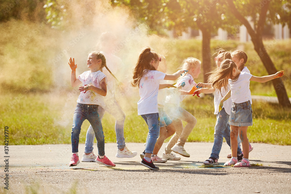 Fototapeta premium Happy smiling girls have fun using Holi colors, in the summer at sunset