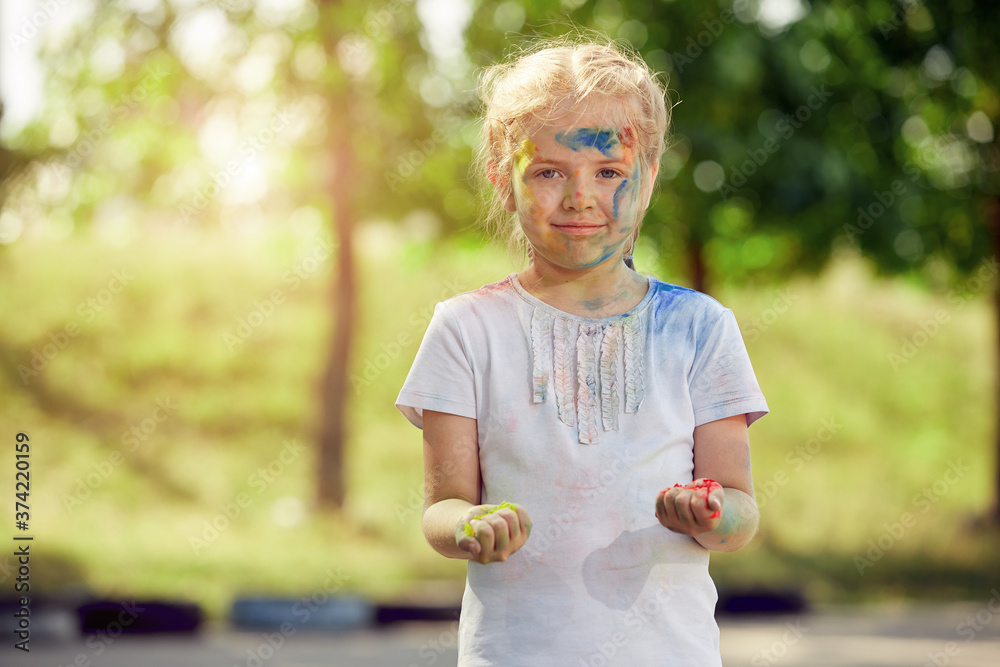 Portrait of a little girl smeared with paint in a white t shirt in a Park Sunny day with powder paint Portrait of a little girl smeared with paint in a white t shirt in a Park Sunny day with powder paint