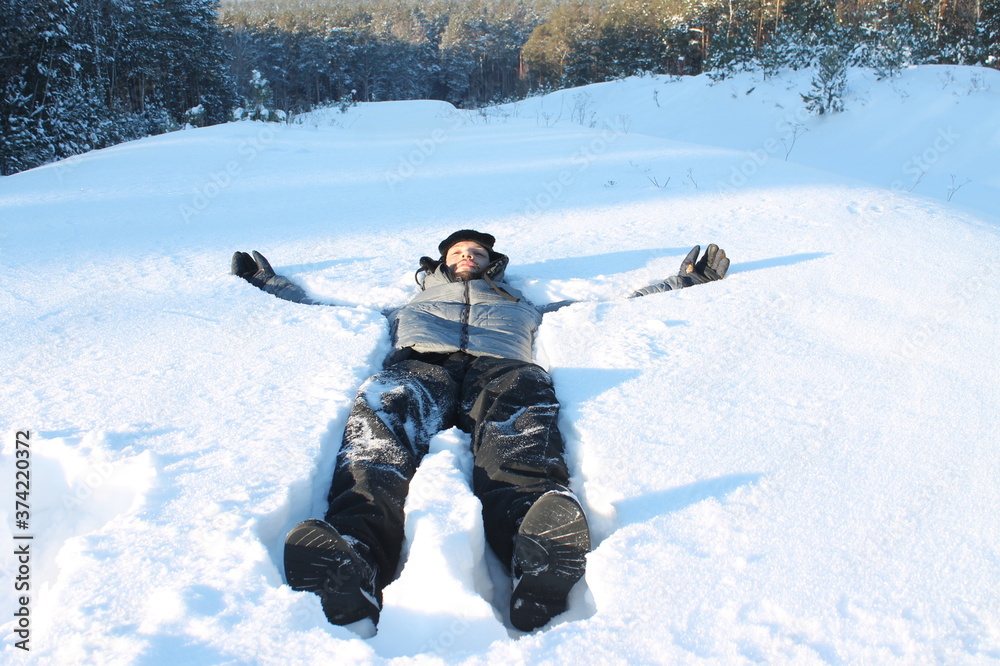 Young man lying in snow with the forest in the background