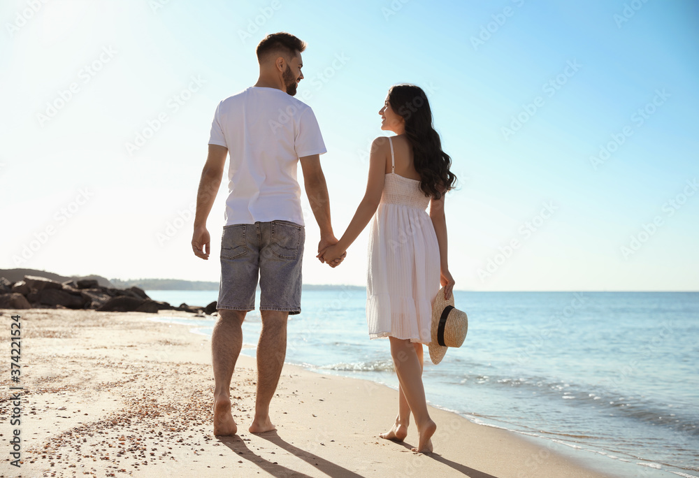 Happy young couple walking on beach near sea. Honeymoon trip Happy young couple walking on beach near sea. Honeymoon trip