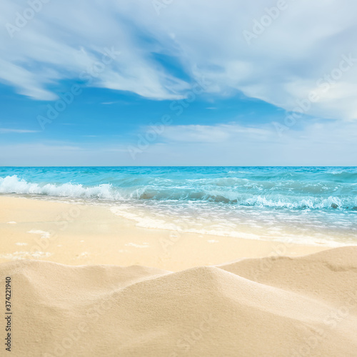 Ocean waves rolling on sandy beach under blue sky with clouds © New Africa