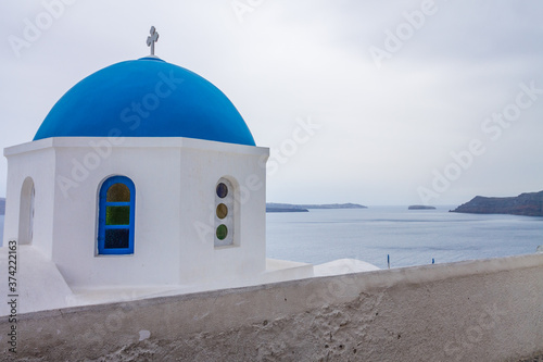 Classic blue dome from Oía, Santorini Island. Ocean view in the background on cloudy day with copy space.