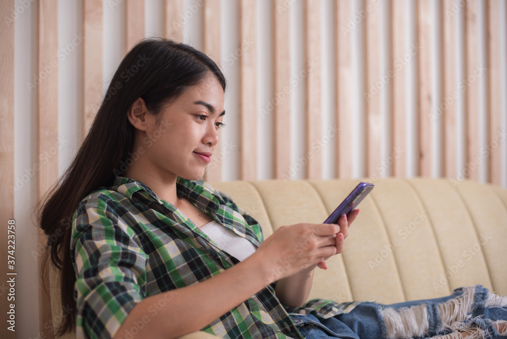 Beautiful young woman in casual clothing using mobile and smiling while working indoors Beautiful young woman in casual clothing using mobile and smiling while working indoors