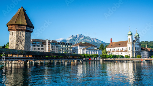 Scenic view of Chapel bridge and Jesuit church with clear Pilatus mount in background and blue sky during summer Lucerne old town Switzerland