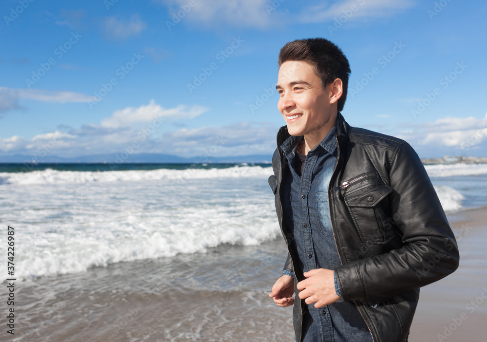 Handsome happy young man smiling walking along the beach on sunny day. Handsome happy young man smiling walking along the beach on sunny day.