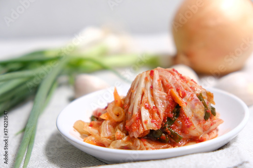 Kimchi is placed in a white plate with a fork on its side. photo