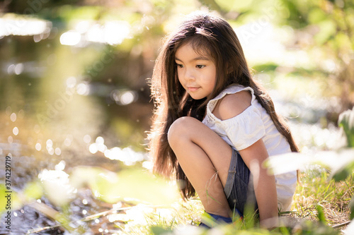 Happy young girl sitting by a creek