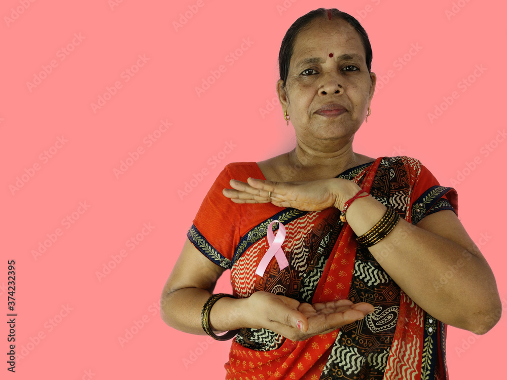 indian Woman in sari with pink ribbon covering by hands for awareness for breast cancer in October month.