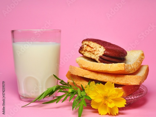 Dry rusk bread, choco pie chocolate and a glass of milk isolated on pink background. Healhty breakfast menu