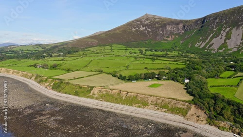 Stunning View Of Lush Fields And Rocky Yr Eifl Mountain At The Coast Of Llyn Peninsula In Wales, UK On A Brilliant Weather - aerial drone - panning shot photo