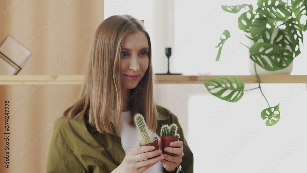 Young female gardener smiles and posing on camera with her favorite little cactuses in hands. Young female gardener smiles and posing on camera with her favorite little cactuses in hands.