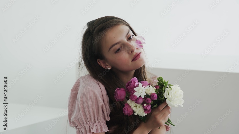 Professional young woman model with flowers looking and posing at camera Professional young woman model with flowers looking and posing at camera