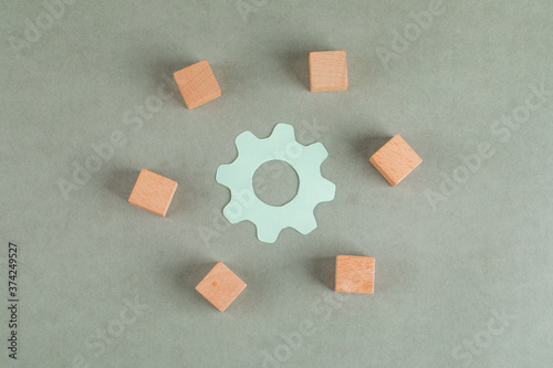 Repair concept with wooden cubes, settings icon on grey background flat lay.
