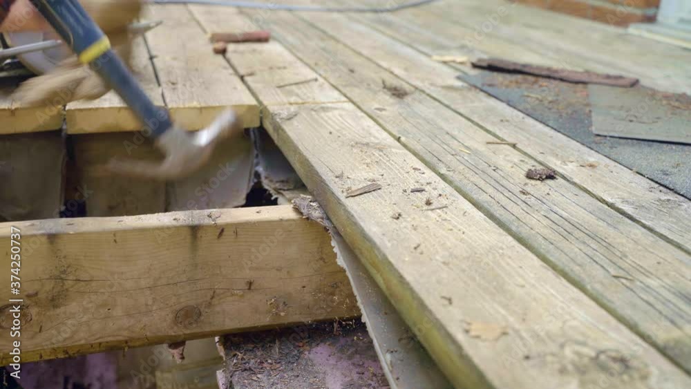 Gloved man removes nail from deck with hammer then lifts board with crow bar Gloved man removes nail from deck with hammer then lifts board with crow bar