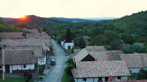 Drone flies over the historical streets of Holloko, Hungary in the sunset. Drone flies slowly forwards photo