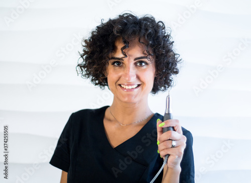 young caucasian woman manicurist master with nail tools is smiling on the white background