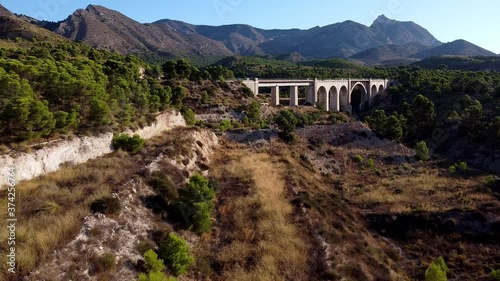 Approaching an old bridge with cyclists passing on it photo