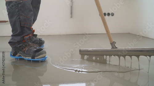 Interior of apartment under construction. Mirror smooth surface of the floor. Floor covering with self leveling cement mortar. Roller application