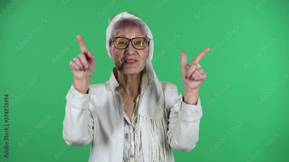 Portrait of old stylish woman is smiling and showing heart with fingers then blowing kiss isolated over green background. Portrait of old stylish woman is smiling and showing heart with fingers then blowing kiss isolated over green background.