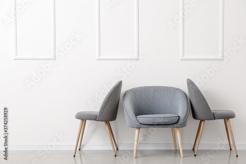 Fototapeta Naklejka Na Ścianę i Meble -  Modern chairs near light wall