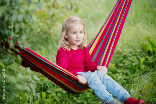 smile little blonde girl in hammock in garden